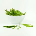 碗中鲜嫩豌豆及散落豆荚