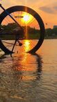 夕阳下自行车轮映于水面