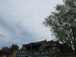 老旧房屋旁的绿树与天空