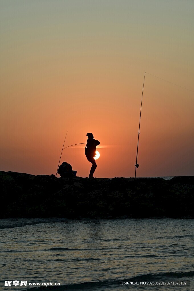 夕阳下的海边垂钓者