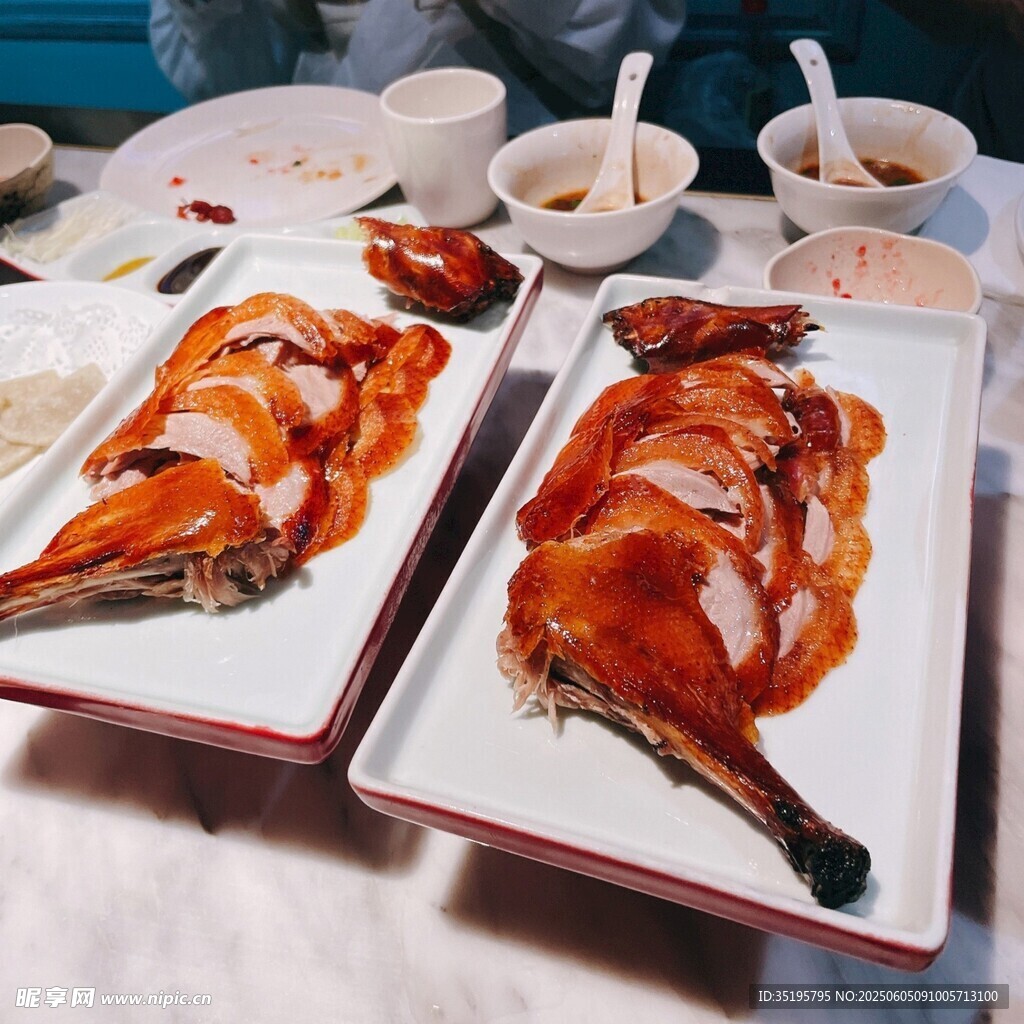 两盘美味烤鸭摆于桌前