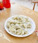一盘美味饺子摆于木桌