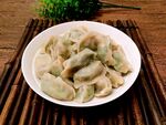 一盘美味饺子摆于竹席上