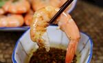 筷子夹虾蘸料特写