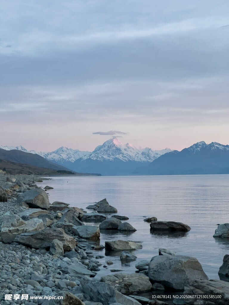 湖畔岩石与远处雪山美景