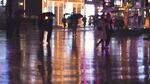 雨夜街头行人的光影倒影