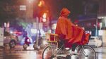 雨夜中骑行的红衣三轮车夫