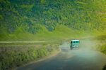 山间公路行驶的绿色客车