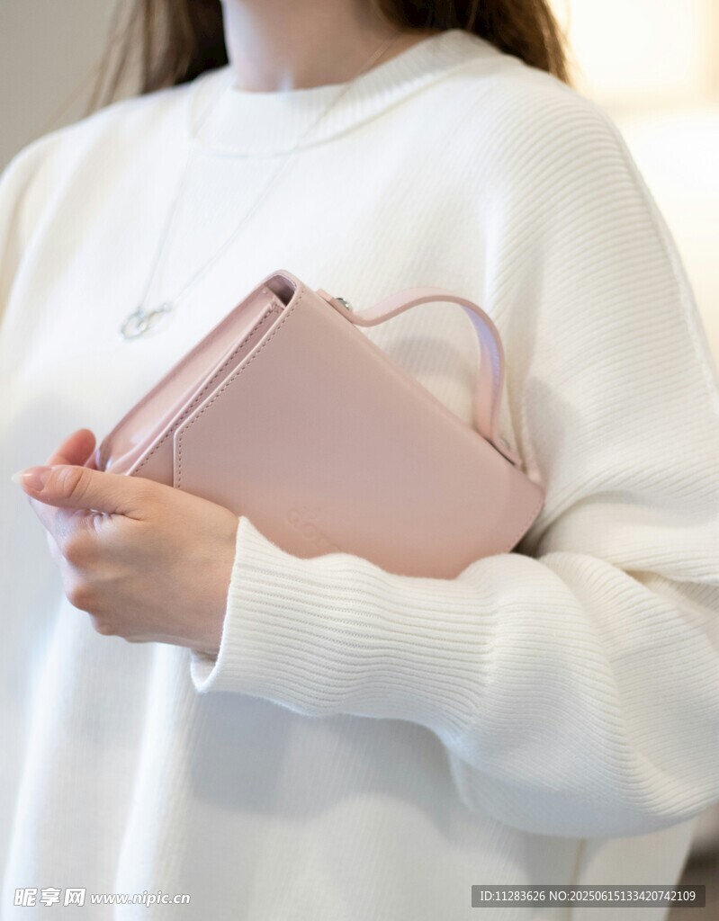 女士手持粉色精致手提包
