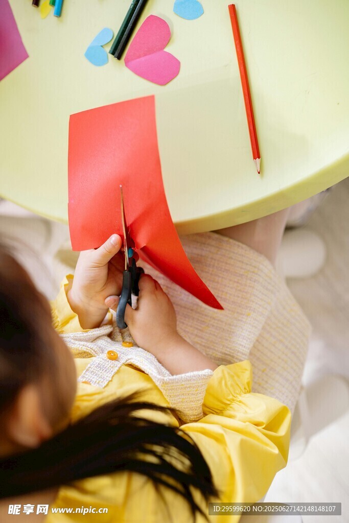 幼儿专注玩红色折纸