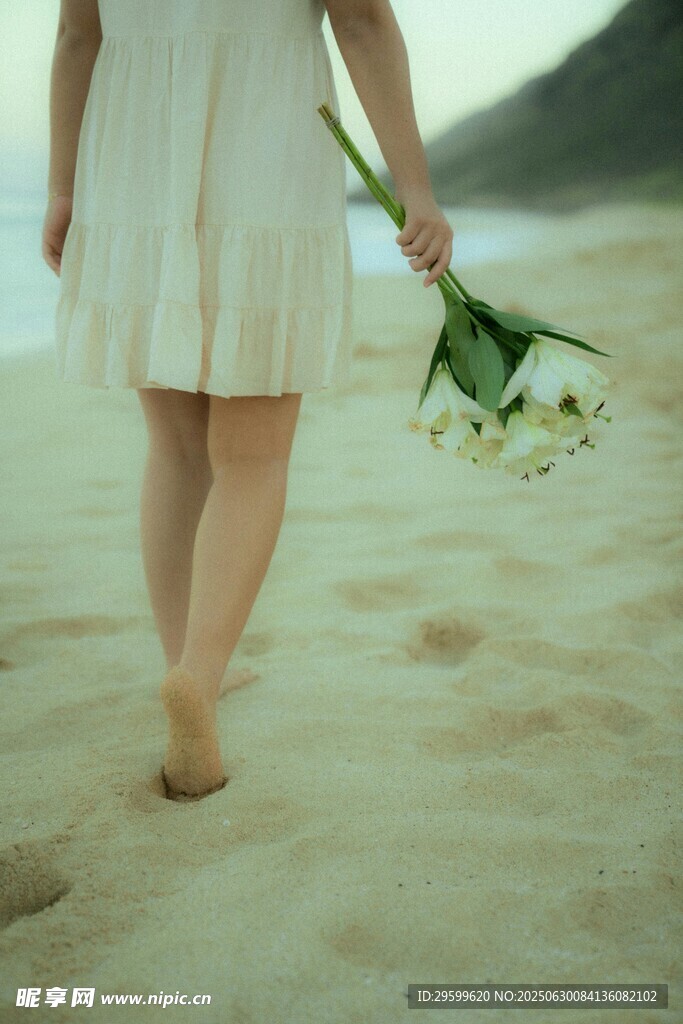 沙滩上持花漫步的女子