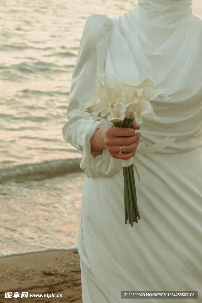 海边手持花束的白衣女子