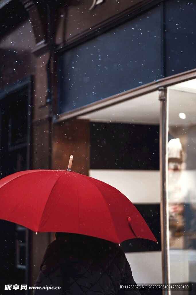 雨中撑红伞的行人