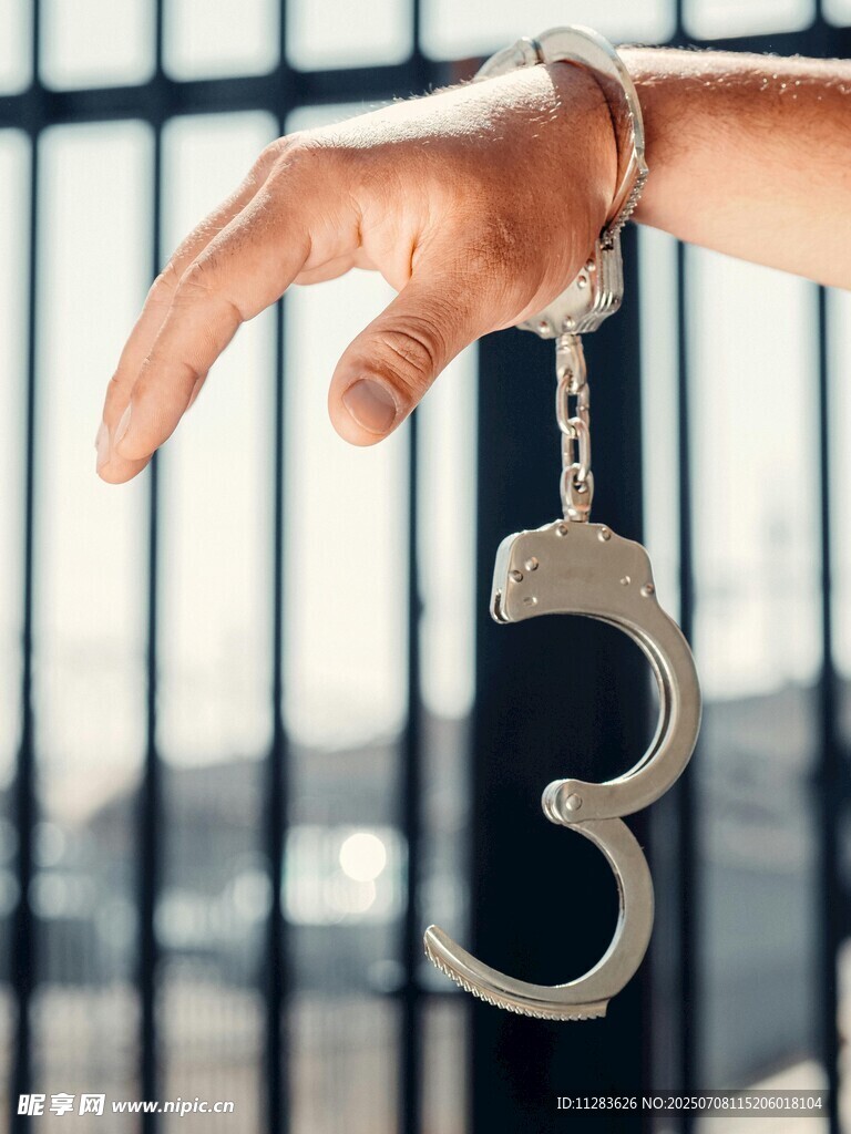手戴手铐于铁栏前