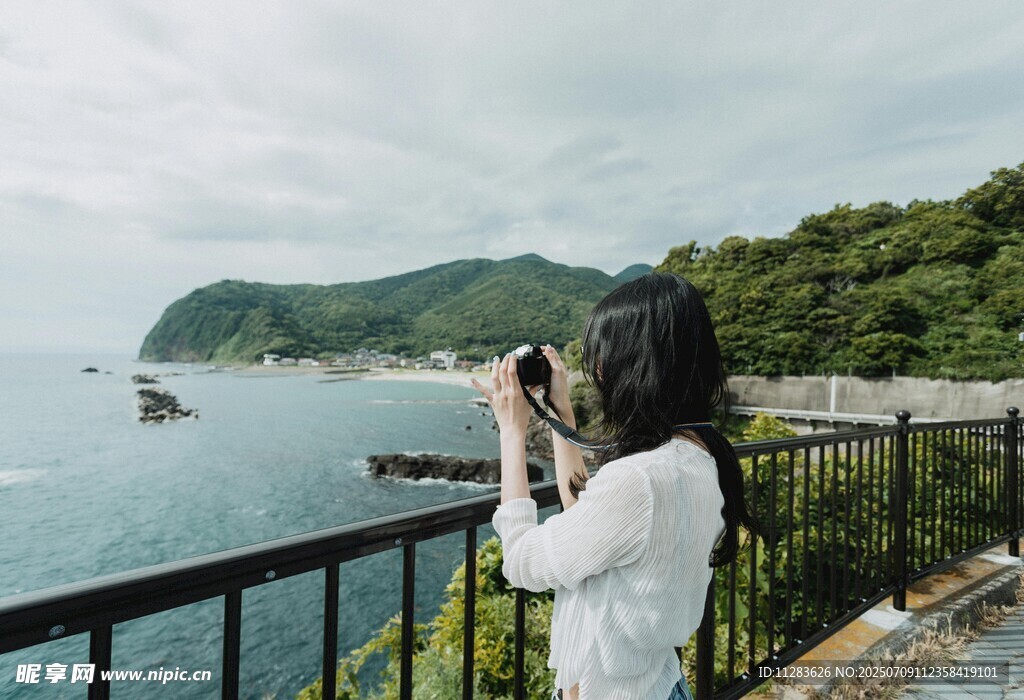 女子凭栏拍摄美丽海景