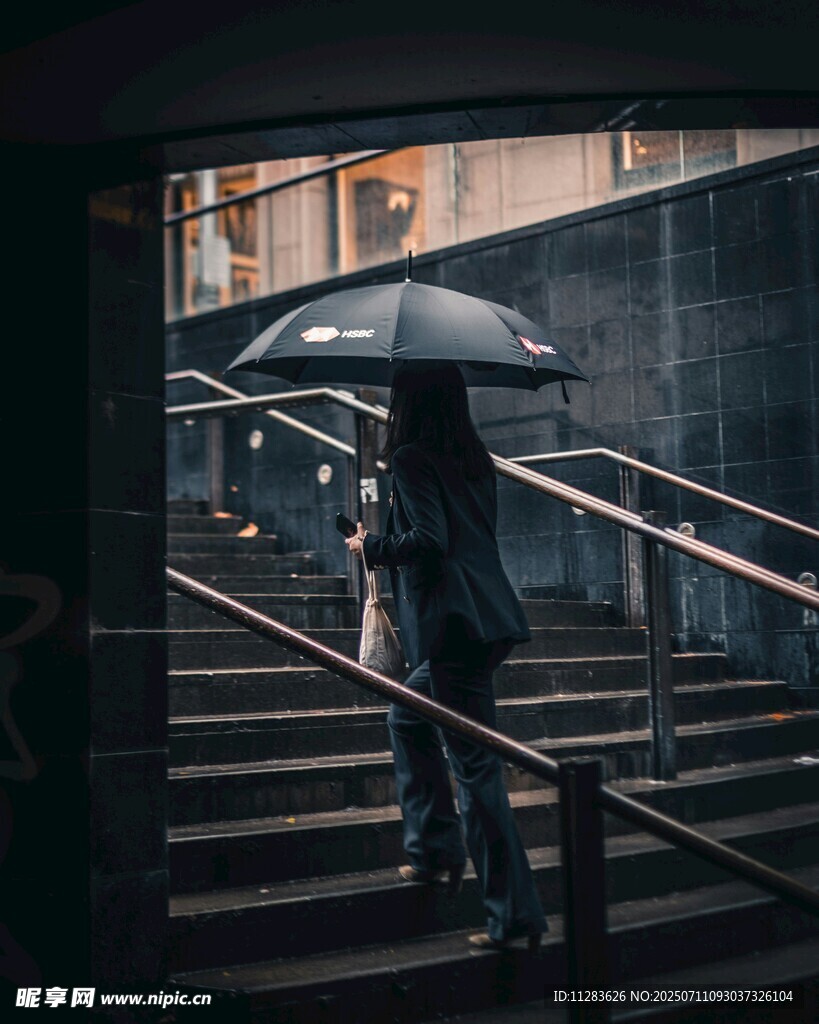 雨中撑伞走在楼梯的身影
