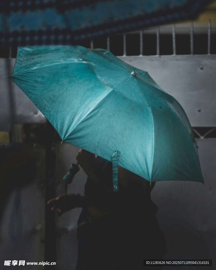 雨中撑蓝伞的模糊身影