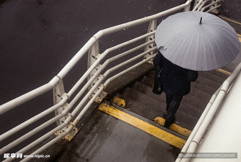 雨中撑伞走下楼梯的身影