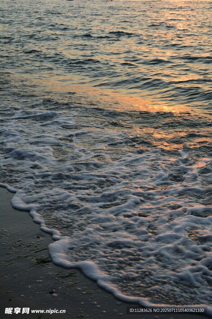 夕阳下的海浪拍打沙滩