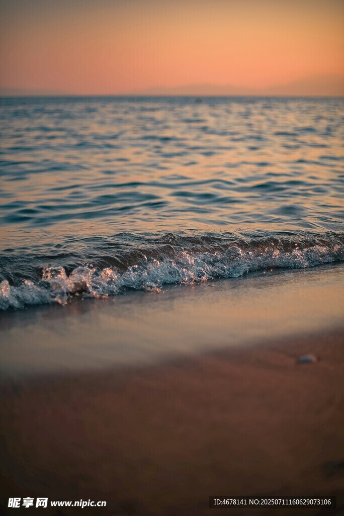 夕阳下的海浪轻拍沙滩