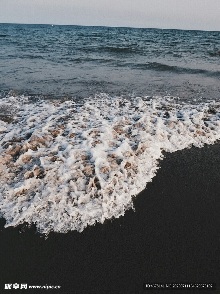 海浪拍打黑色沙滩瞬间