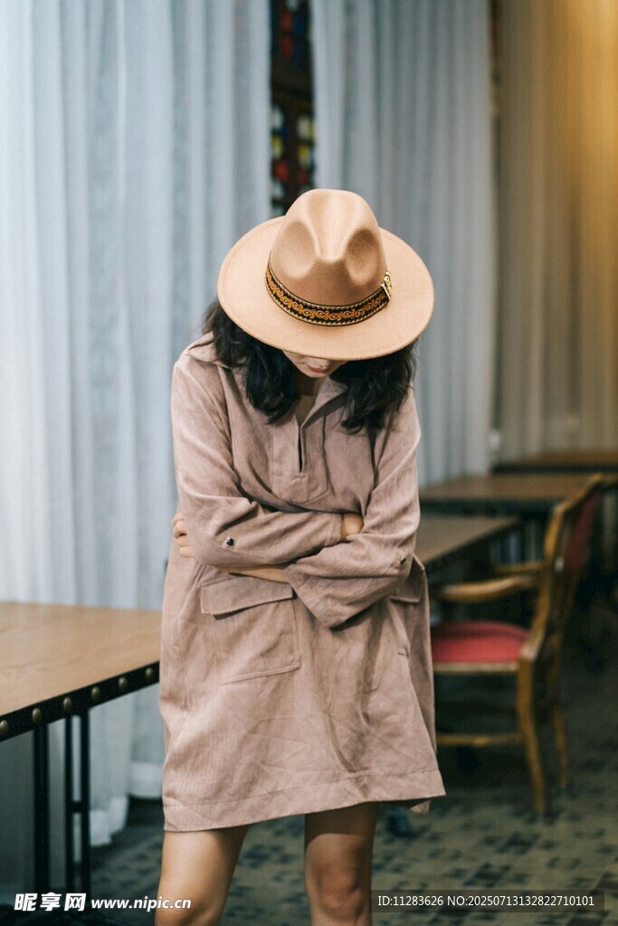 戴帽女子抱臂于室内