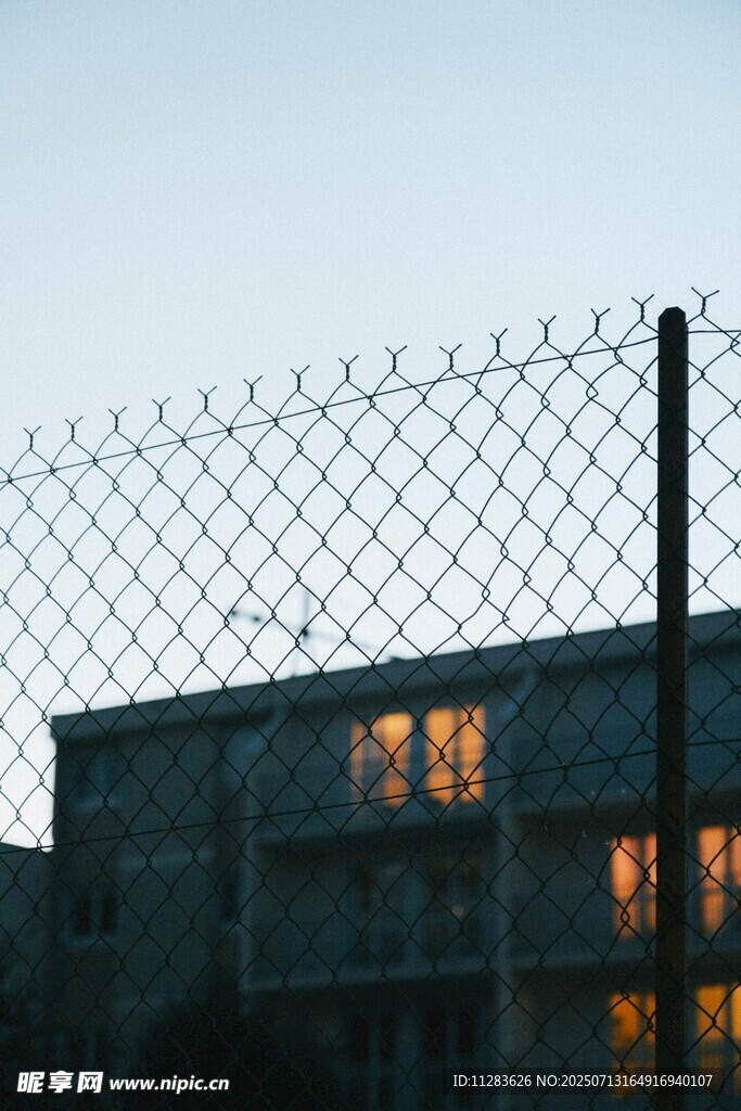 铁丝网后的建筑灯光