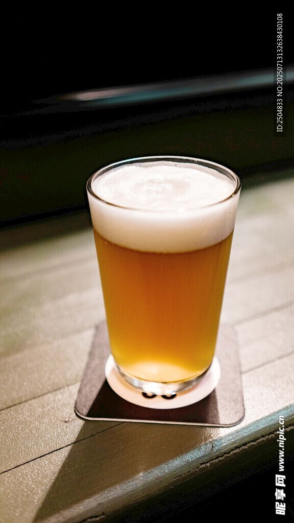 木桌上的一杯泡沫啤酒