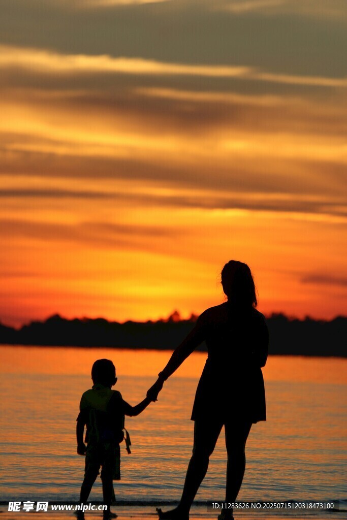 夕阳下母子海边温馨漫步