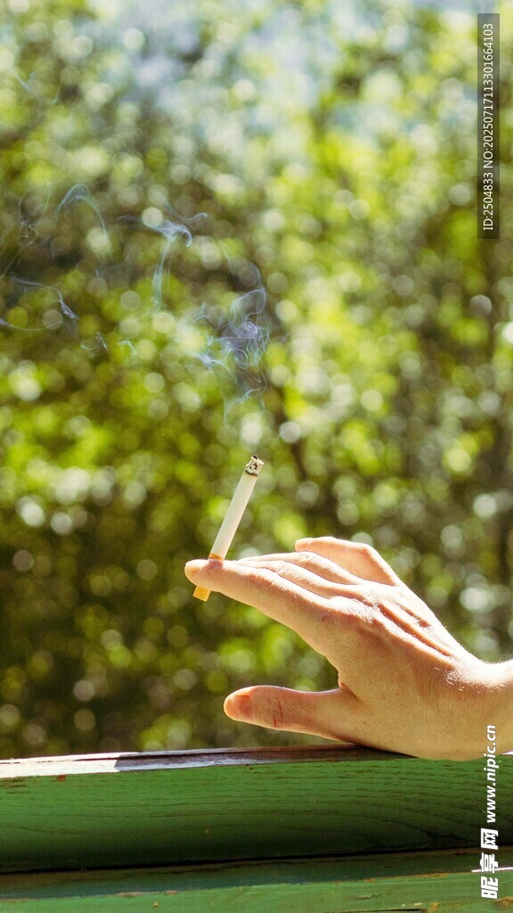 手托香烟于户外绿意间