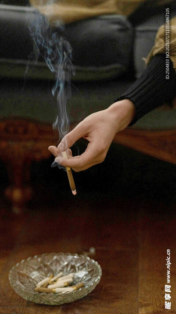 手捻香烟置于烟灰缸旁