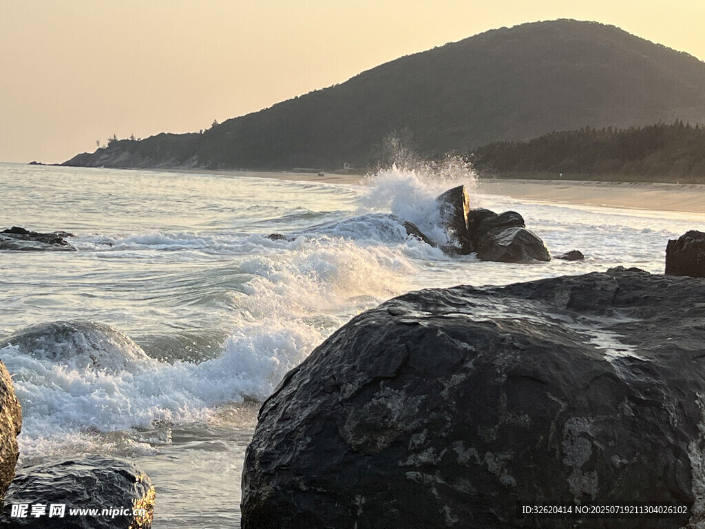 夕阳下海浪拍打礁石美景