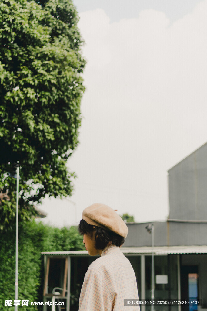 戴帽女子于绿植旁远望