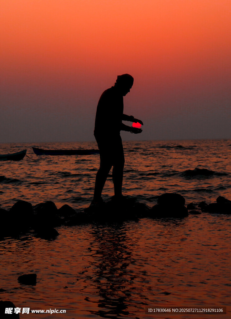夕阳下海边持物的孤独身影