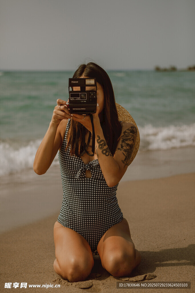 海滩上拍照的纹身女子