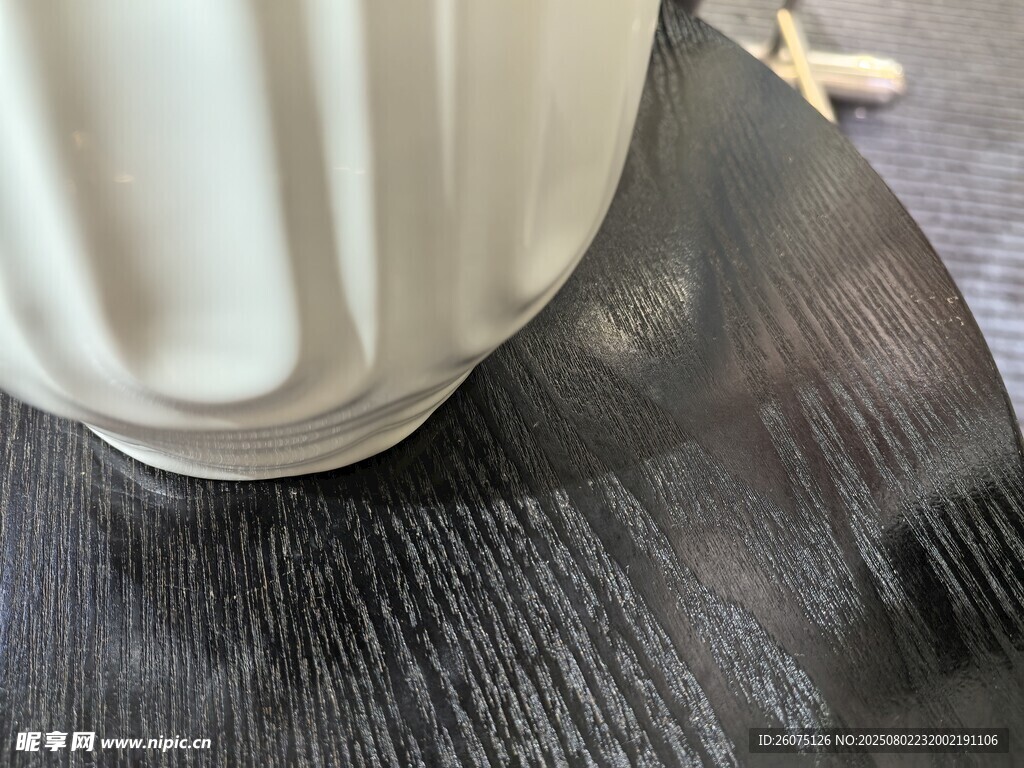 白色花瓶置于深色木质纹理表面
