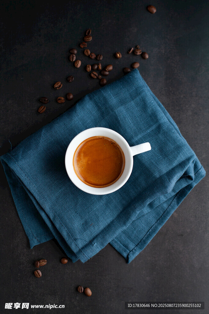 蓝布上的咖啡杯与咖啡豆