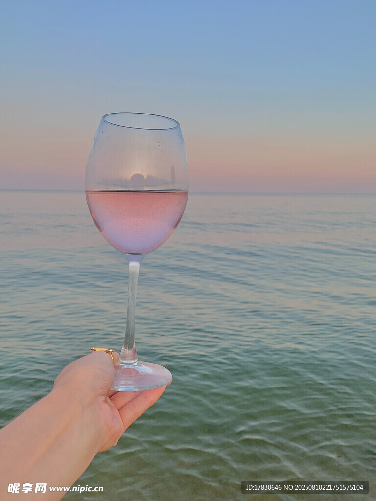 海边手持粉红酒杯的惬意时刻