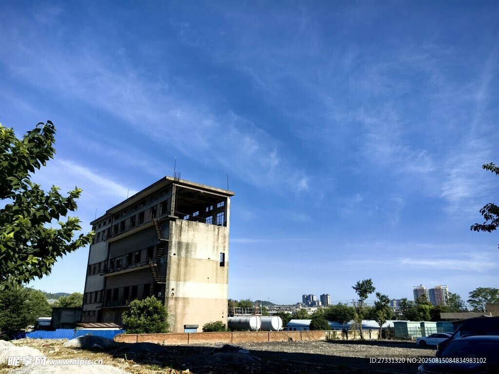 老旧建筑矗立蓝天绿树间