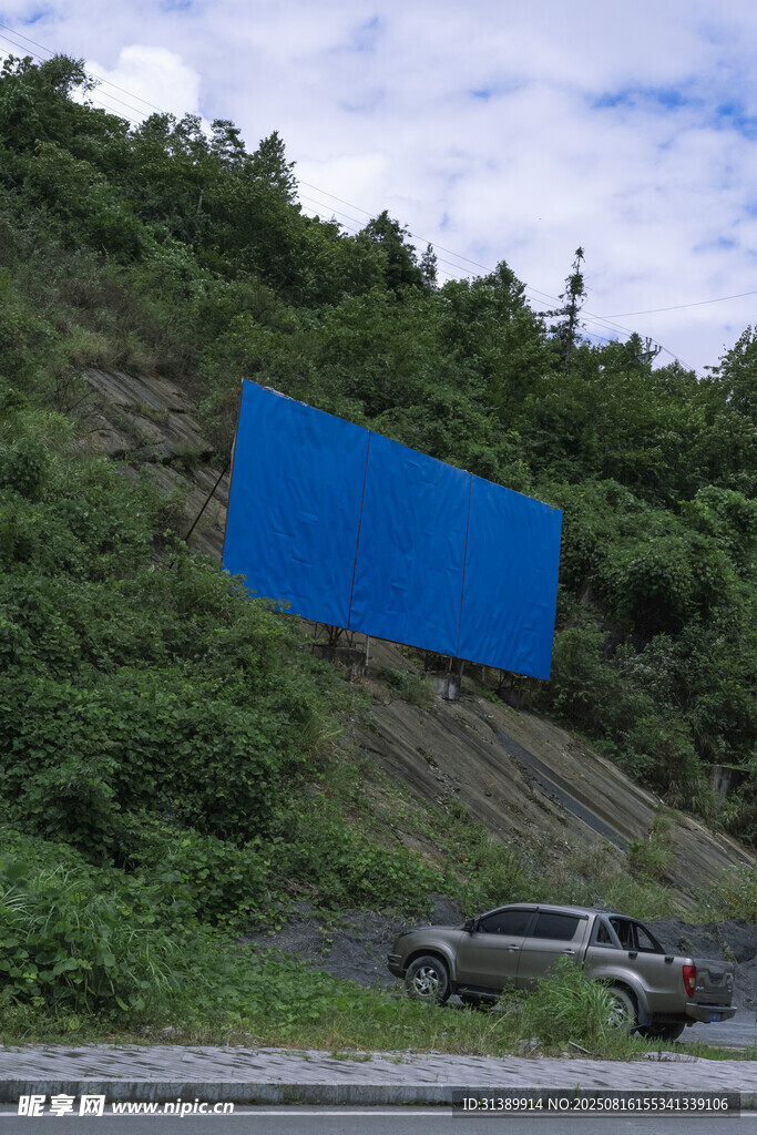 山坡旁的汽车与蓝色广告牌