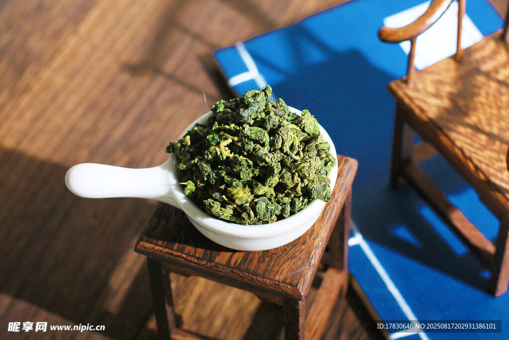 木桌上瓷勺盛着的绿茶叶