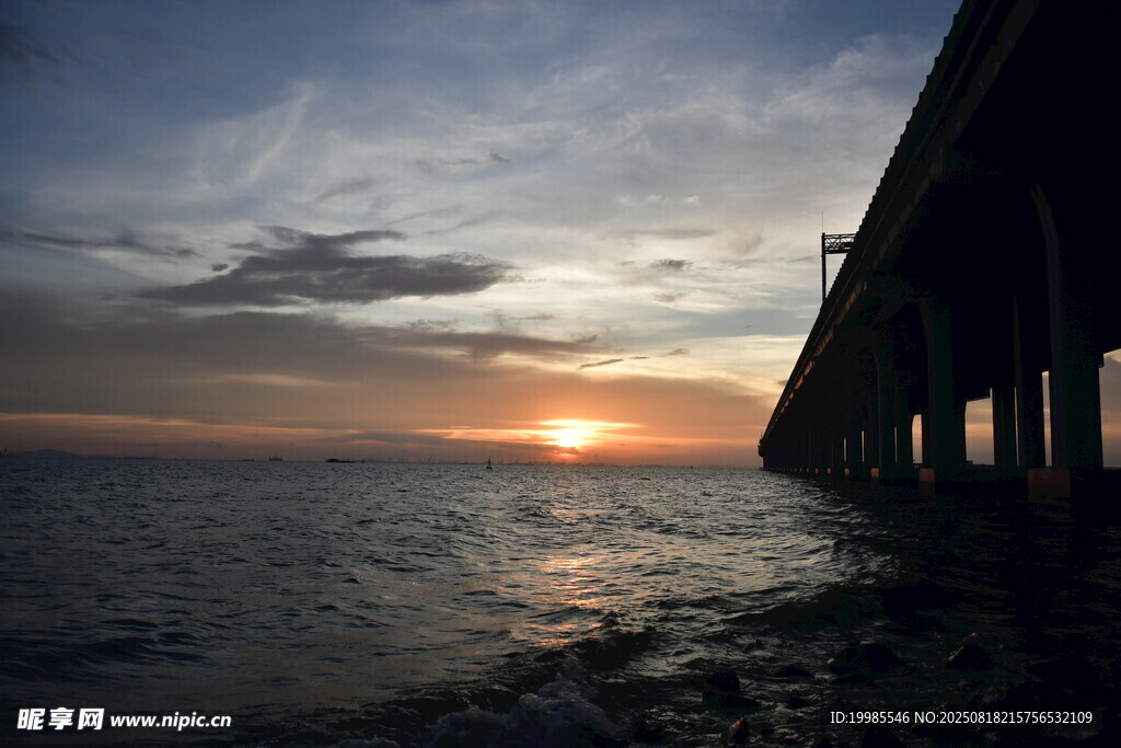 夕阳下的海边桥梁剪影