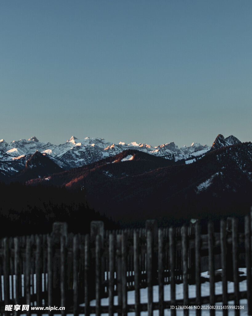 雪覆山峦前的木栅栏景观