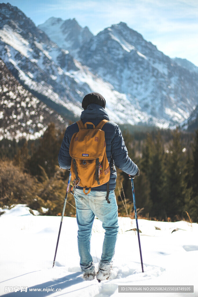 雪地徒步者背向巍峨群山