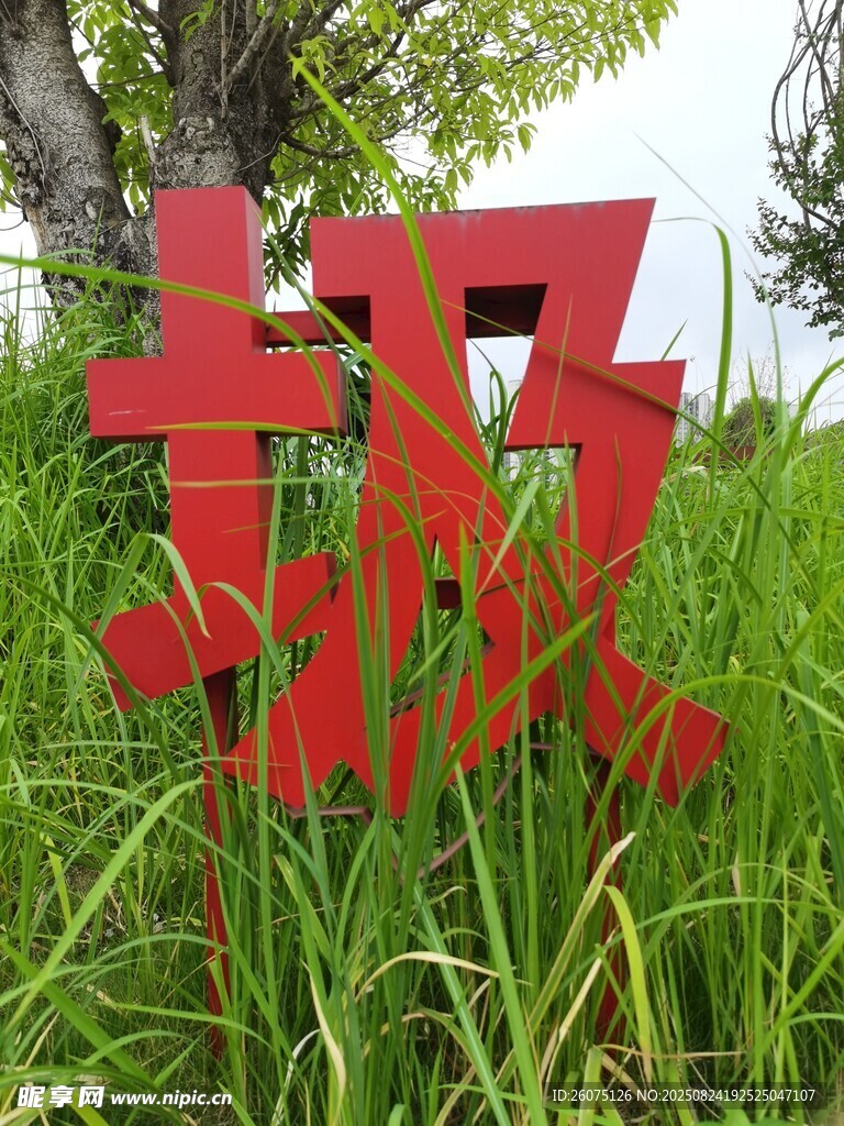红色立体字立于葱郁草丛中