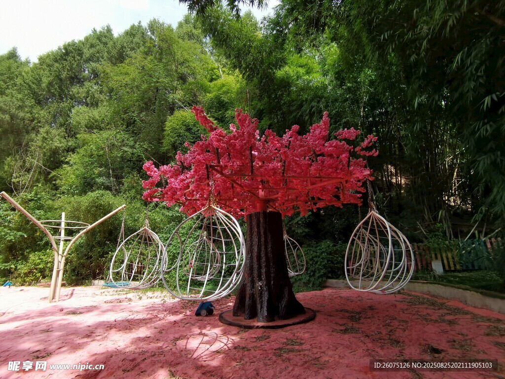 红色沙池里的秋千树与绿植背景