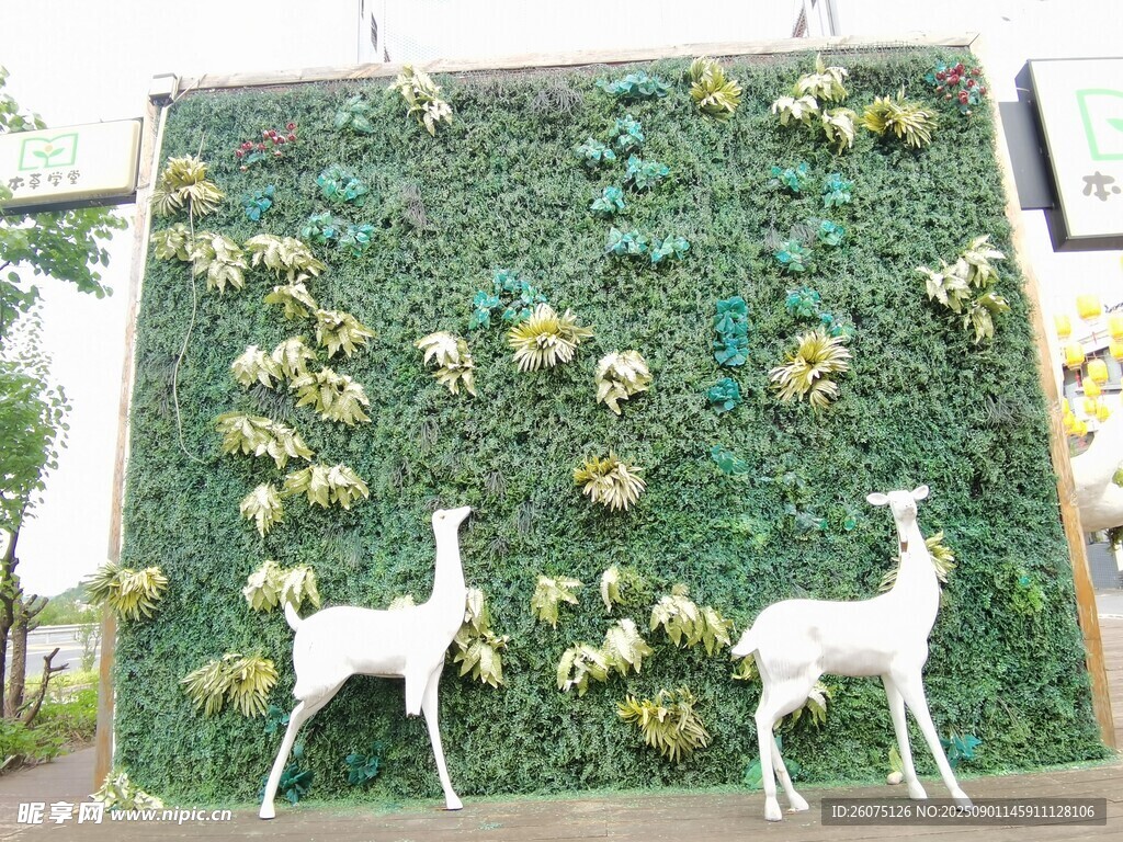 绿植墙前的白色小鹿摆件