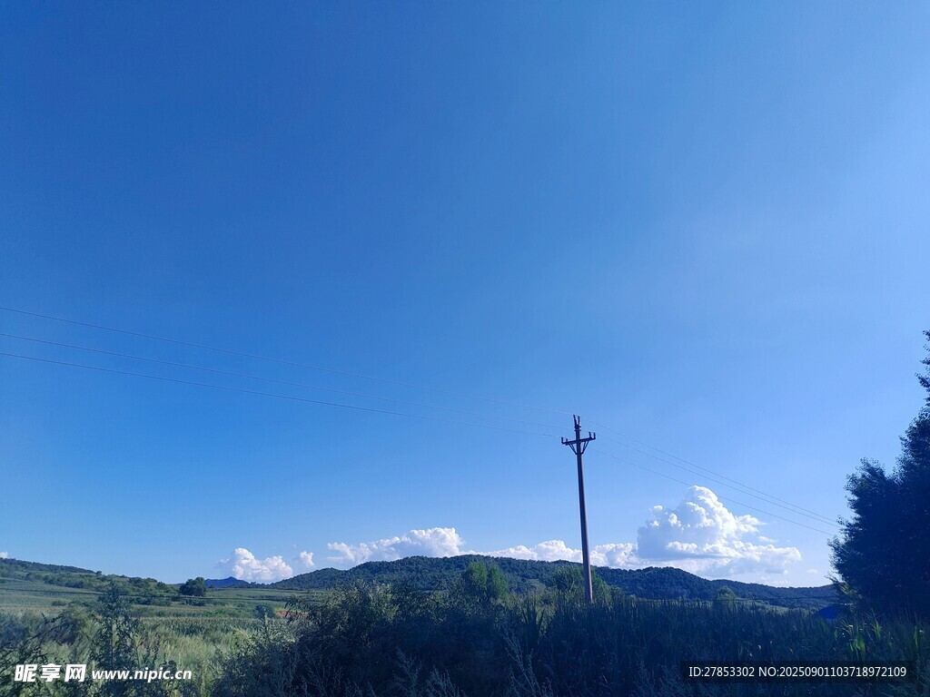 蓝天青山间的高耸电杆