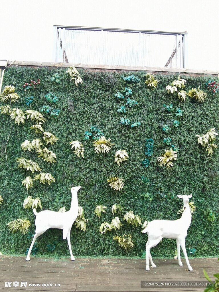 仿真绿植墙前的白色小鹿摆件