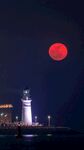 月夜灯塔旁的红月景观
